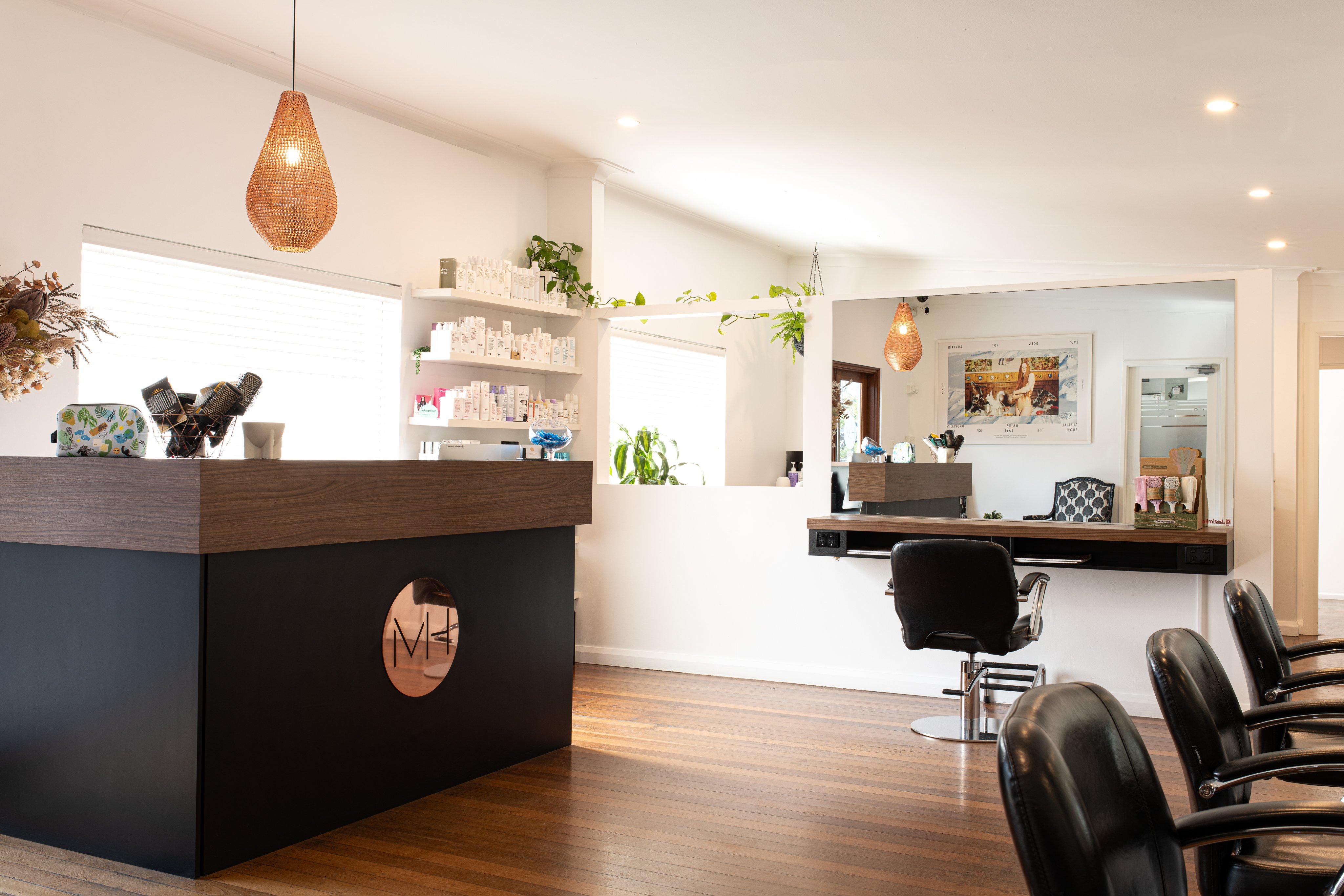Hair salon with reception desk, black leather chairs and rose gold fittings.
