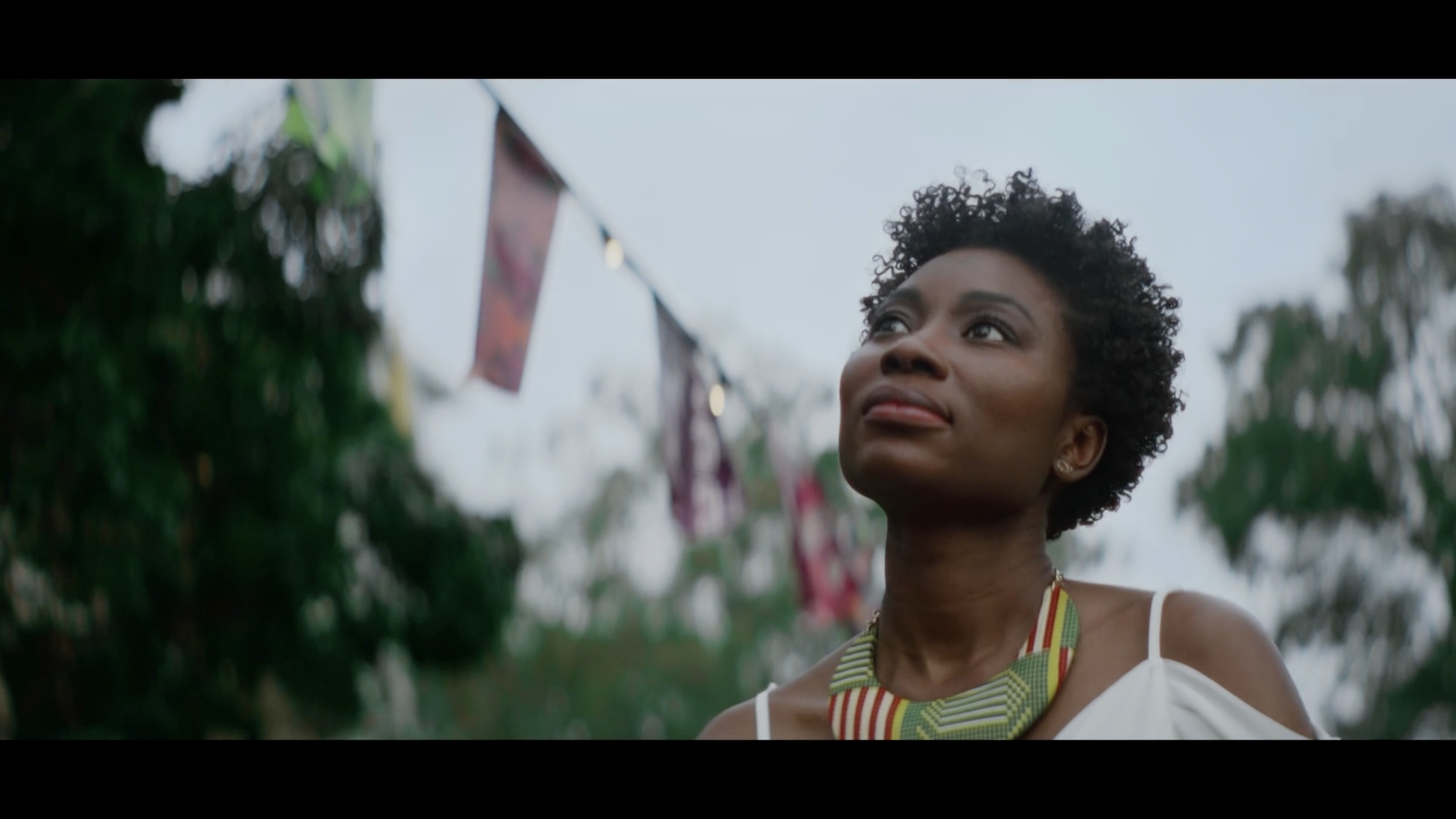 A woman wearing beaded jewellery looks up while walking