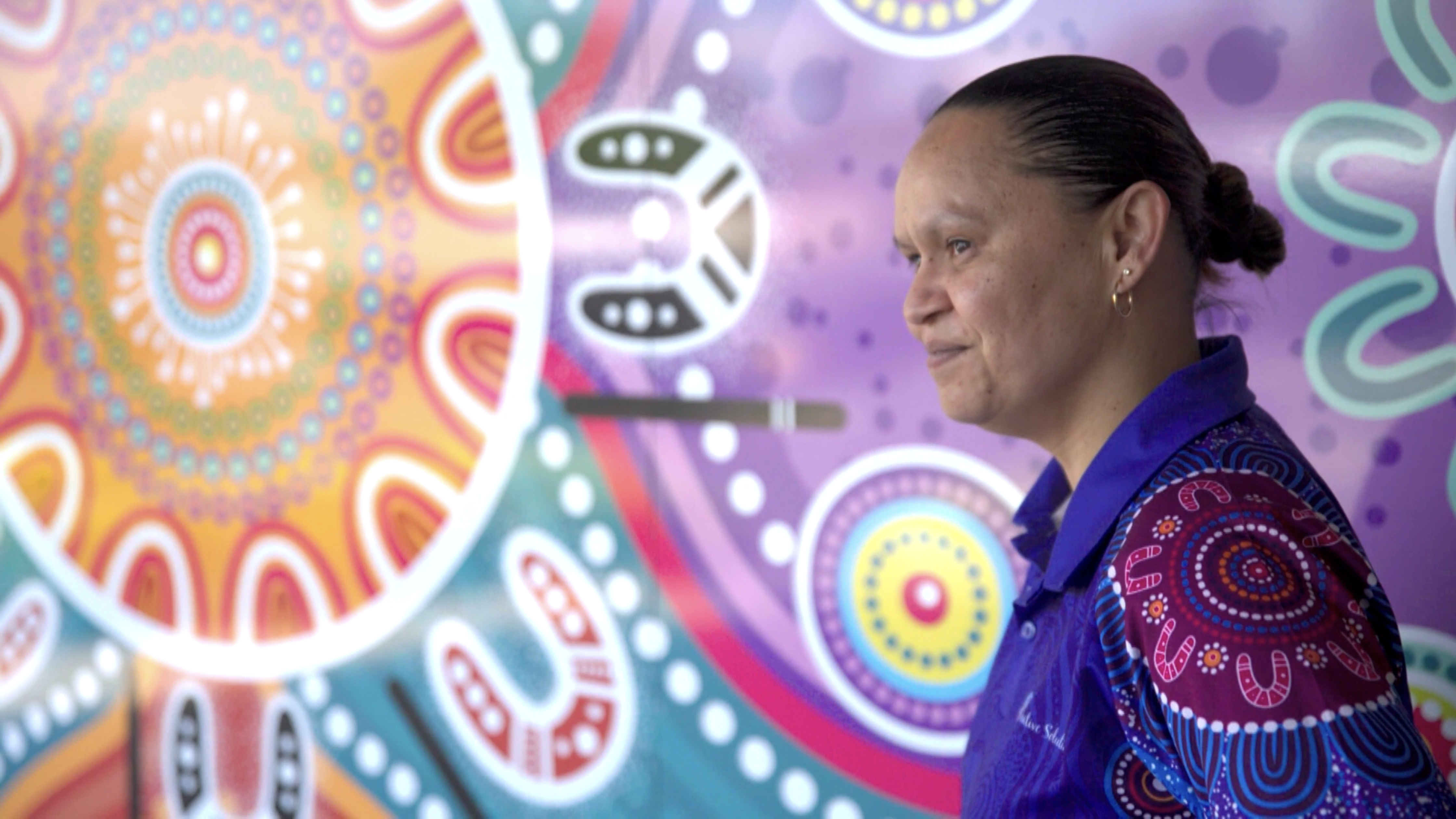 Woman artist stands with a design mural