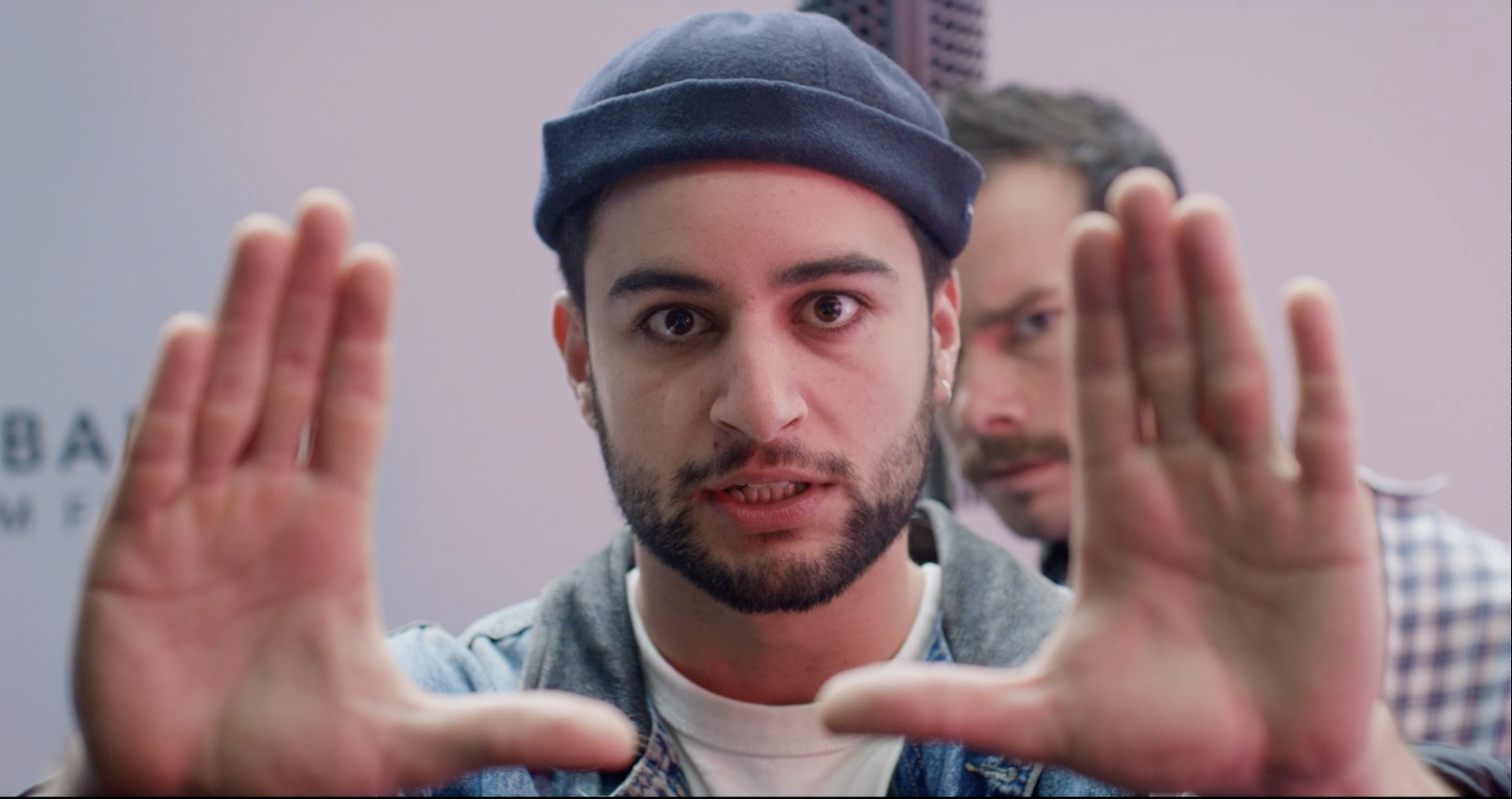 Man holding hands up to 'frame' a photo looking back at you